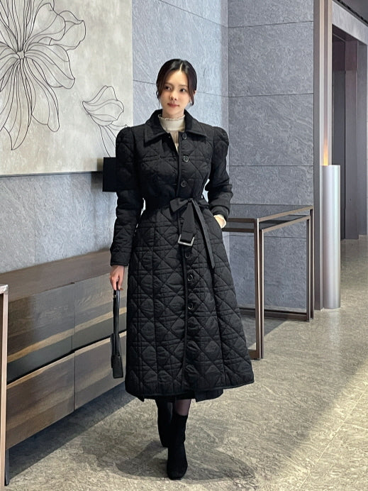 ブラックのダイヤキルティング中綿ロングコートを着用したモデルの全身コーデ、ウエストベルトでくびれを作るフレアシルエットのきれいめ通勤アウター。