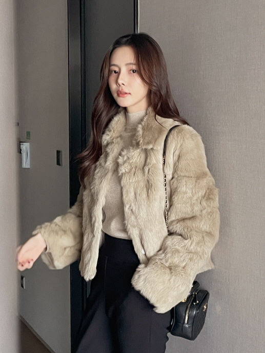 ベージュのフェイクファーショートコートを着た女性が廊下を歩いているシーンで、柔らかい質感が映える大人フェミニンな冬アウターコーデ