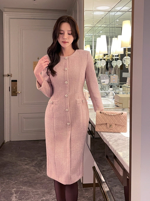 上品なピンクツイードワンピースを着た女性がホテルのパウダールームでポーズをとるシーン。クラシックでエレガントなデザインが映える、オフィスやフォーマル向けの大人フェミニンコーデ。