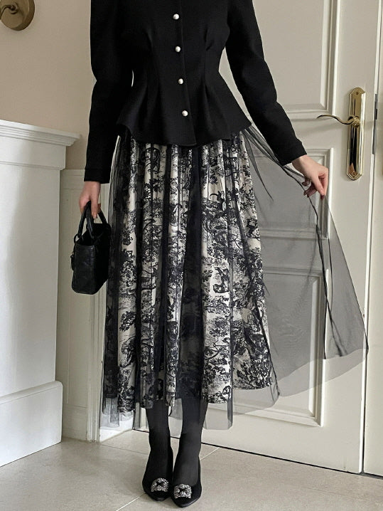 ブラックチュールを軽く持ち上げ、トワル柄スカートのレイヤードデザインを見せる女性の全身コーデ。上品なモノトーンとふんわり広がるシルエットがクラシックな大人フェミニンスタイルを演出。
