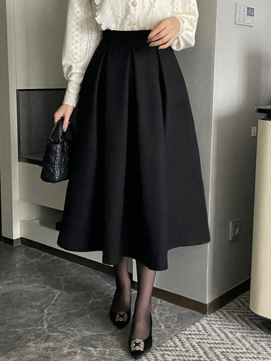 フリルとレースが華やかなアイボリーの長袖ブラウスに、ハイウエストの黒フレアスカートを合わせた上品なオフィスカジュアルコーデを室内で撮影した着用イメージ。